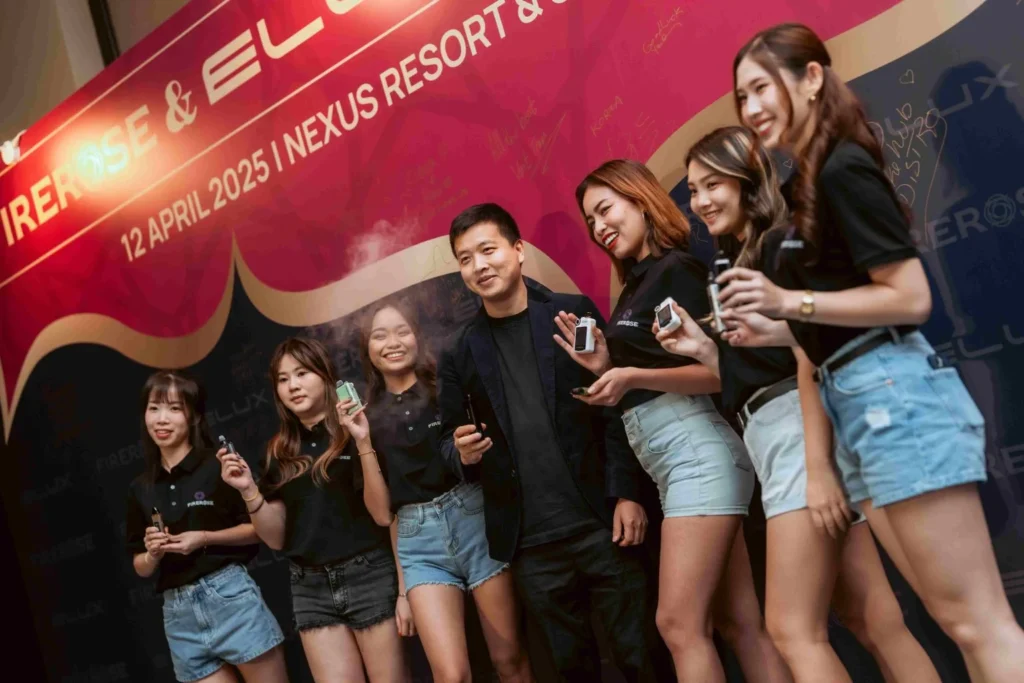 Spark Fest Carnival l Karambunai Hotel 12 Group poses at a branded event wall while holding products during a nighttime launch gathering photo session