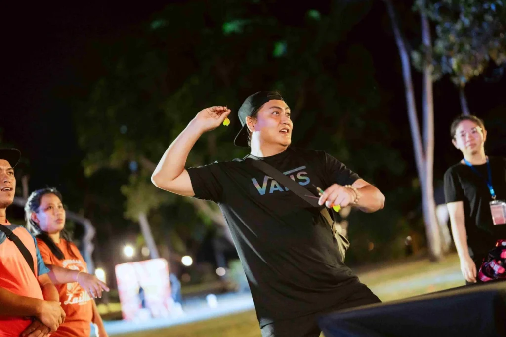 Spark Fest Carnival l Karambunai Hotel 8 Participant prepares to throw a dart during an outdoor night game while onlookers watch from the side