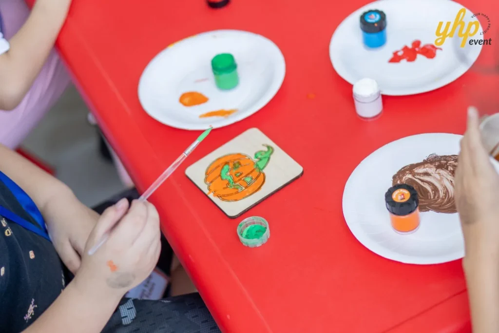 Super Kids Explorer: An Exciting Adventure at Bukit Bantayan 18 High angle shot of a child hand-painting a wooden pumpkin craft with a fine-tipped brush
