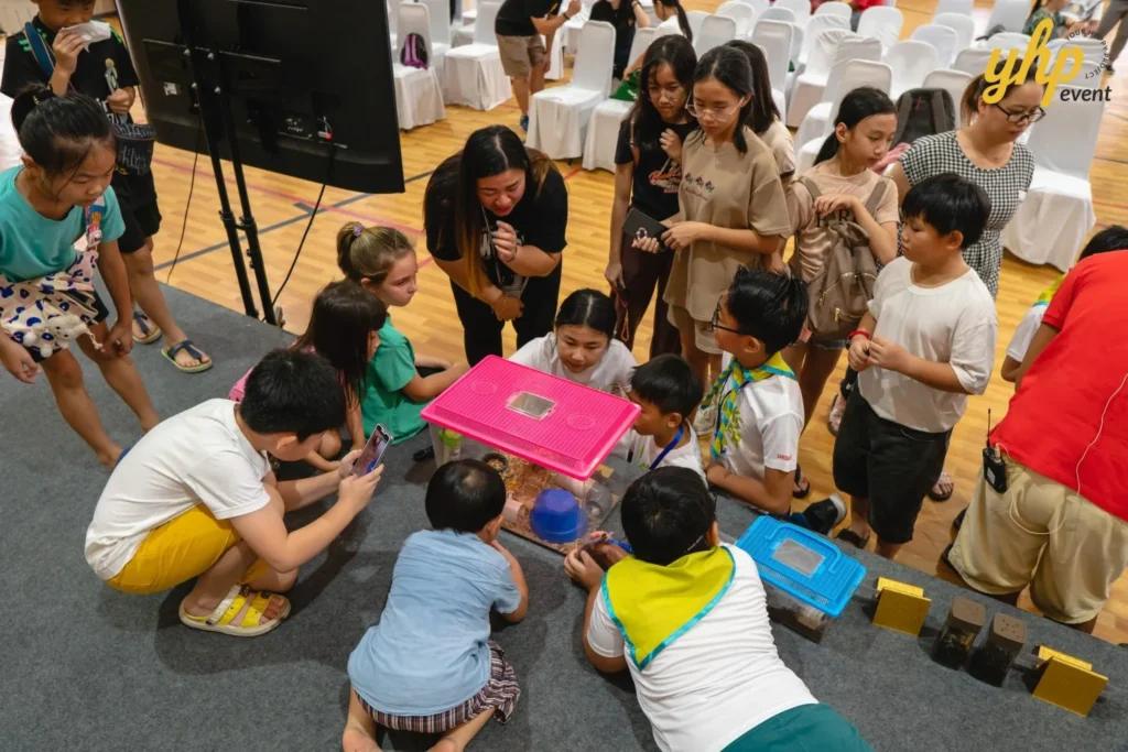 Super Kids Explorer: An Exciting Adventure at Bukit Bantayan 23 Group of children gathered around a pink enclosure to see small exotic animals at a busy pet show event
