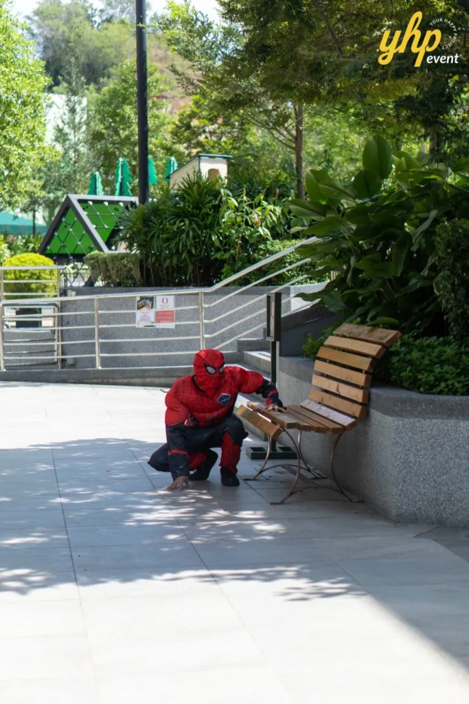 Super Kids Explorer: An Exciting Adventure at Bukit Bantayan 6 A person dressed in a Spider-Man costume crouches near a park bench