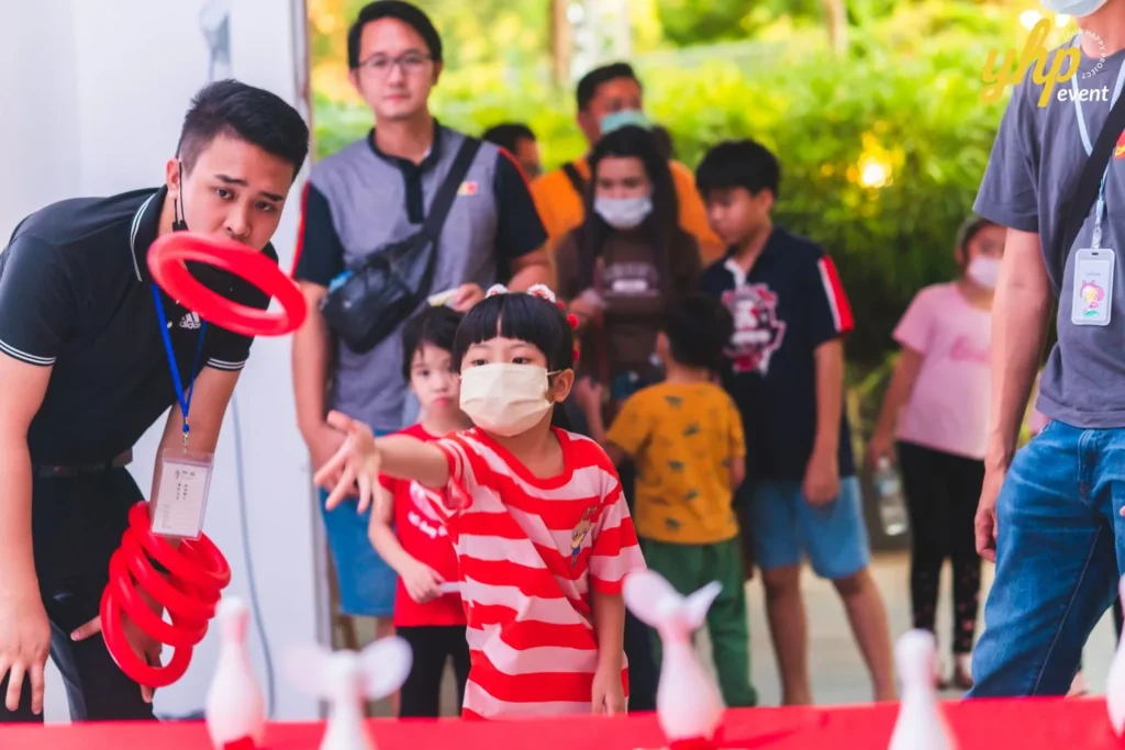 #TooHuattoHandle Lunar New Year Celebration 20 Young boy plays a ring toss game with miniature pins as families gather around an interactive festival booth at Bukit Bantayan Residence.