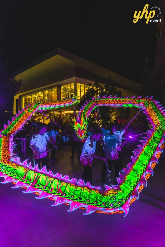 #TooHuattoHandle Lunar New Year Celebration 6 Illuminated dragon dance performance at night with neon colors glowing in front of a Bukit Bantayan Residence.