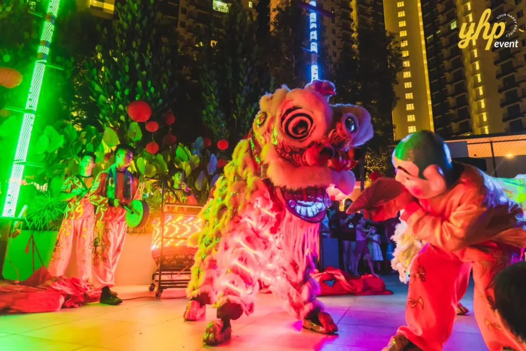 #TooHuattoHandle Lunar New Year Celebration 7 LED-lit lion dance performer facing a masked character during a vibrant nighttime celebration with musicians nearby