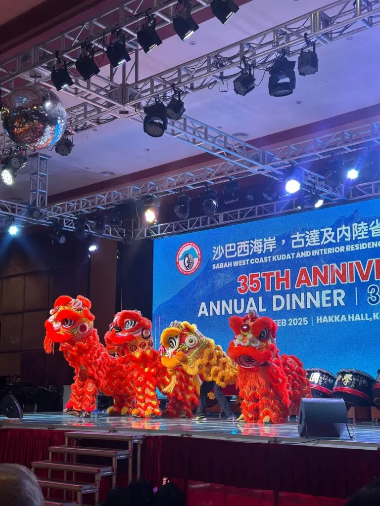 Tyre Association 35th Anniversary Celebration in Kota Kinabalu 10 Red and gold lion dance troupe performs on stage in front of an anniversary dinner backdrop and spotlights