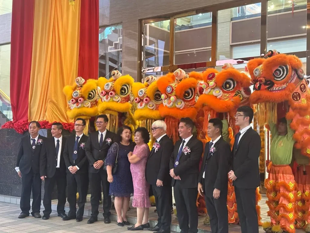 Tyre Association 35th Anniversary Celebration in Kota Kinabalu 7 Group portrait with suited attendees and lion dance performers beside red and gold drapery at the entrance of Hakka Hall Kota Kinabalu